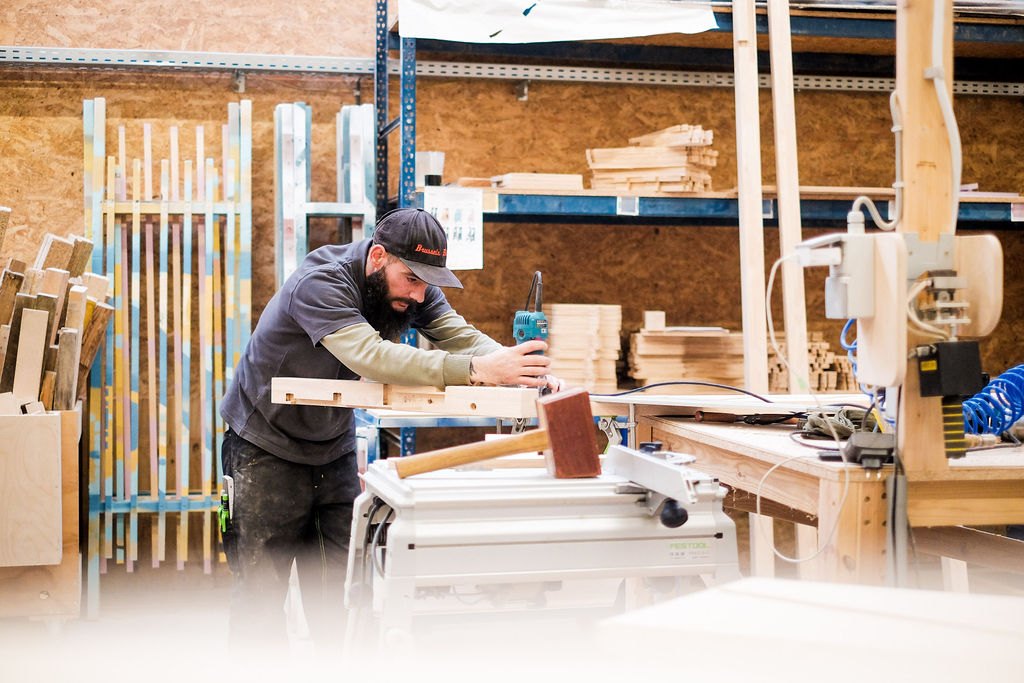 Menuisier Elysta façonnant une pièce en bois dans l’atelier de Coutisse, près d’Andenne