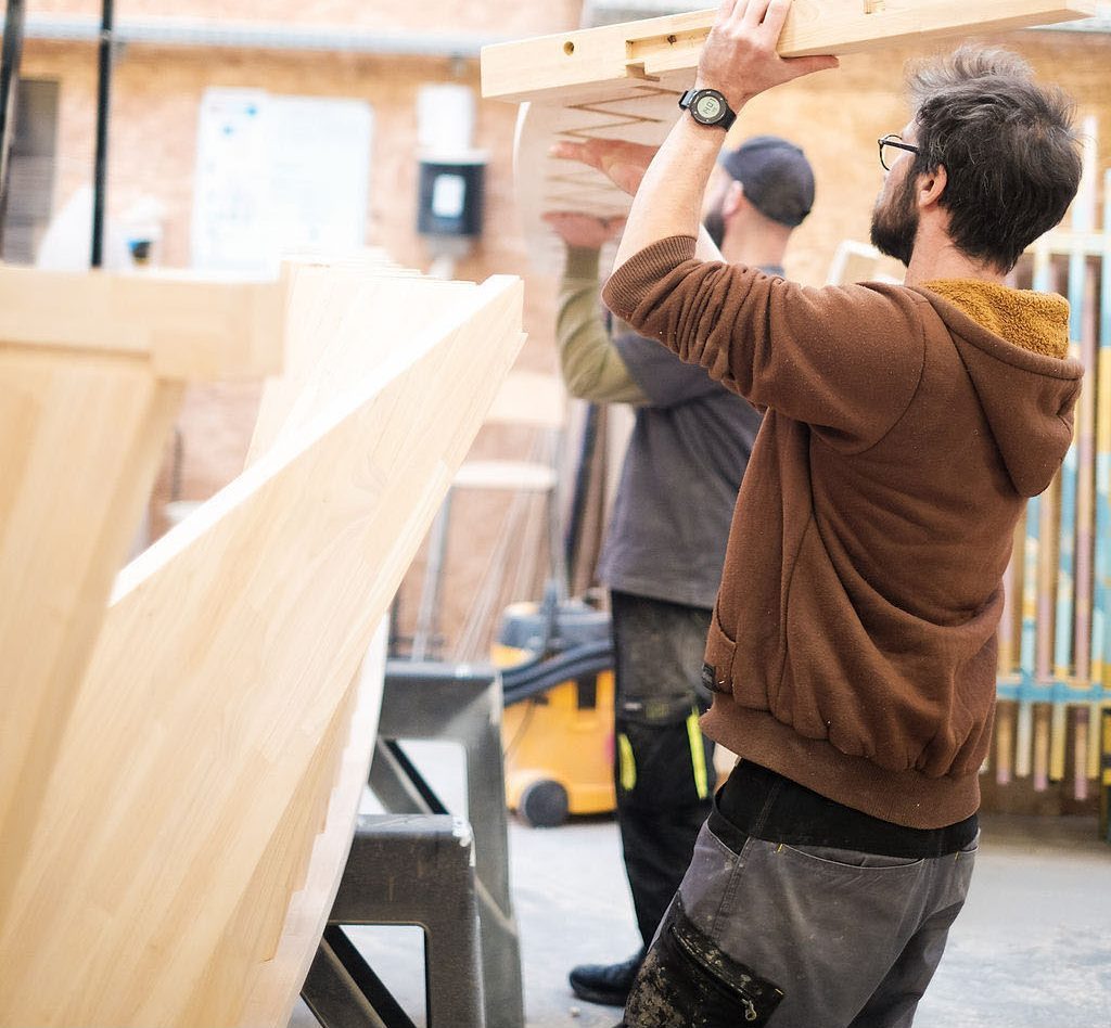 Deux menuisiers Elysta assemblant un meuble en bois à l’atelier
